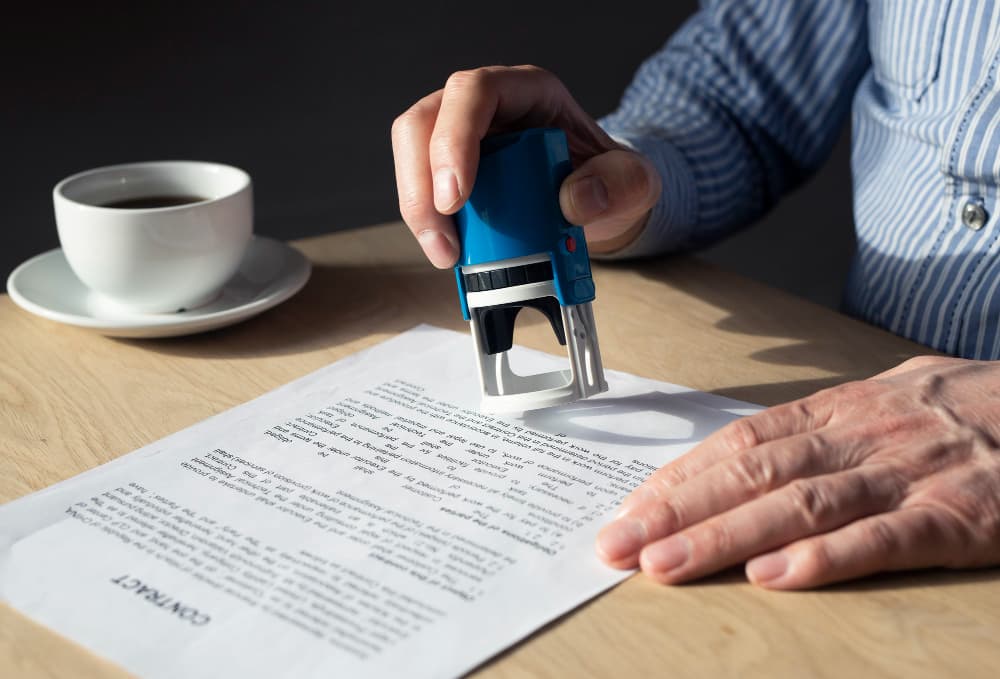 A man is cutting a piece of paper with a blue cutter.
