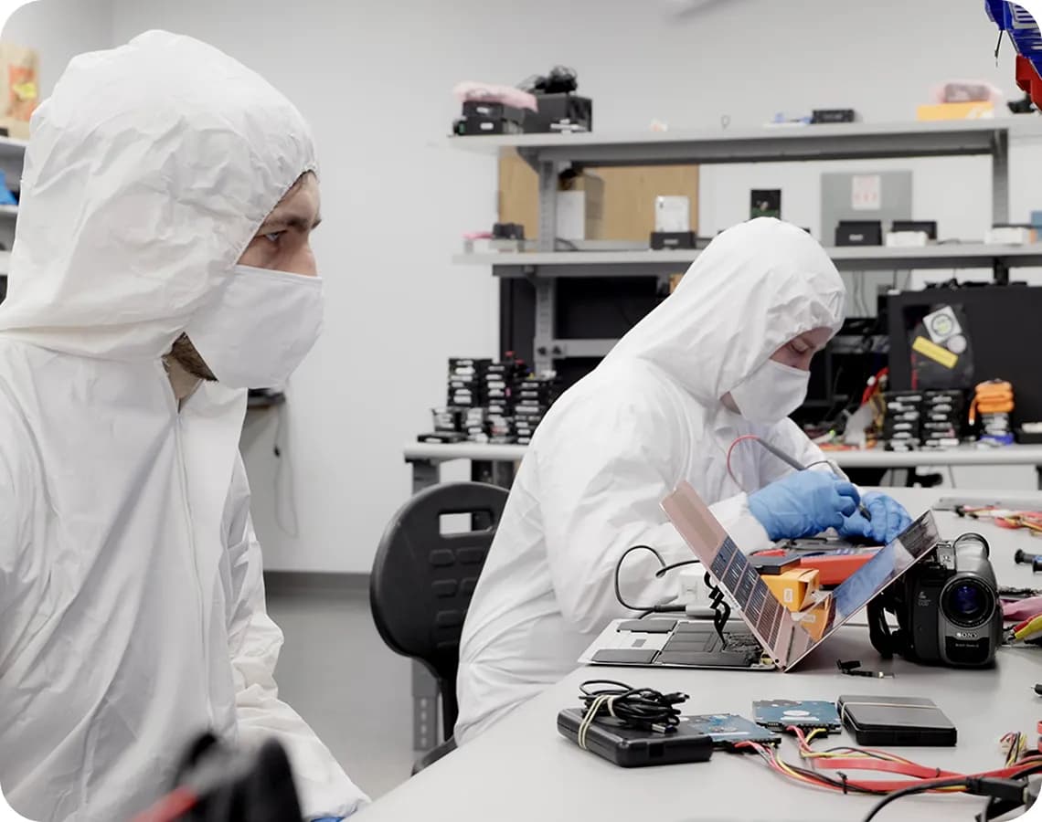 Two men wearing white suits are working on a laptop.