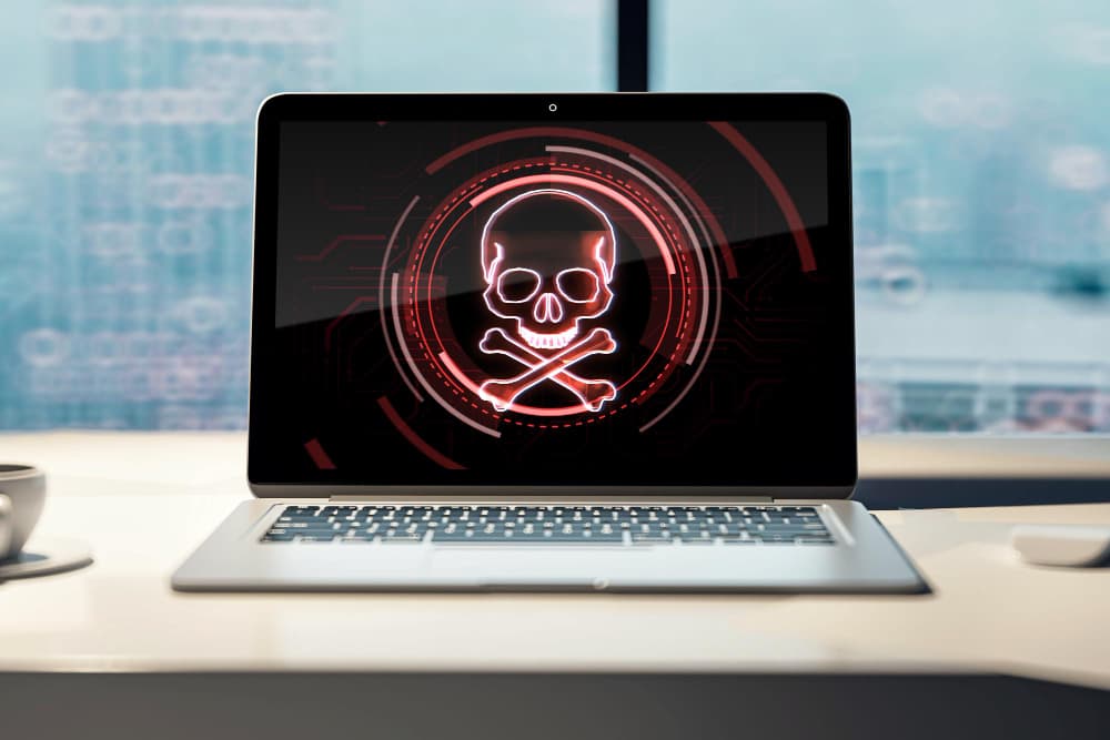 A laptop with a skull and crossbones on the screen.